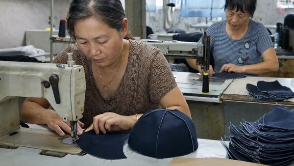 Cap panels being sewn at a sewing machine